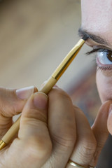 Closeup of professional makeup artist working with beautiful young woman at home. Makeup eye with a brush.