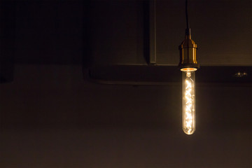 retro light bulb hangs from ceiling near counter bar in dark room,  tungsten light lamp decoration