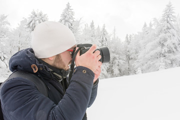 Fototapeta na wymiar a man in a snowy winter forest with a backpack and a camera