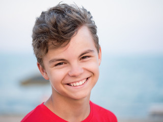 Happy smiling teen boy on beach - summer vacation, close-up portrait. Child looking at camera. 