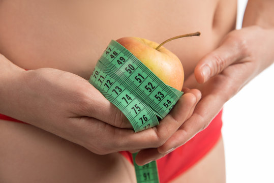 Girl on a diet measuring waist and abdomen centimeter and looks much fat