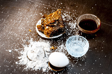 Popular Asian/Indian Ramzan special dish i.e. METHA CHILLA or sugared chapati with ghee and all its ingredients which are egg,sugar,honey and pure ghee on a wooden surface in dark Gothic colors.