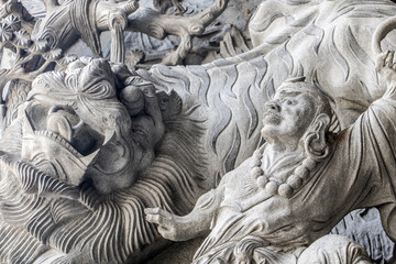 The mythology scene with stone tiger as a decoration on the facade of the Chinese monastery.