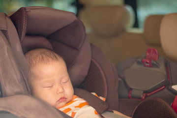 baby boy is sleeping in  safety seat, car seat.