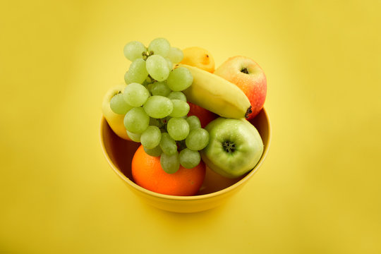 Yellow bowl with fruit stock images. Various fruits on a yellow background. Fruit mix images. Fruit Bowl
