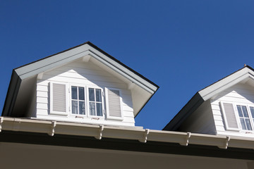 The roof of the house with beautiful window in the blue sky background.