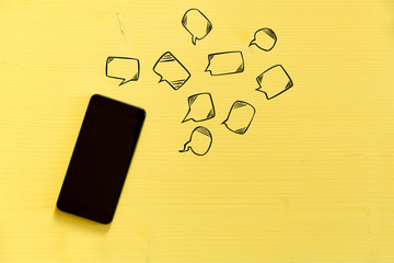 Smartphone on yellow background with text bubbles around. Messaging, texting and connection concept