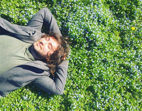 uomo sorridente sdraiato sul prato di primavera