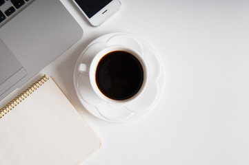 Flat lay on white wooden workspace with laptop computer, cell phone gadget and black coffee. Copy space, background, top view.