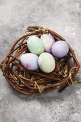 Multicolored eggs for Easter in nest on gray background. Top view, copy space. Food background