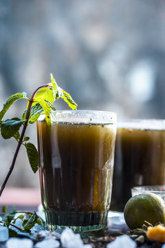 Close up of Asian popular summer drink i.e. Phudina ka shrbat or mint drink with all  its ingredients on a wooden surface which are sugar,mint leaves with its extract,lemon,jaggery and black salt.