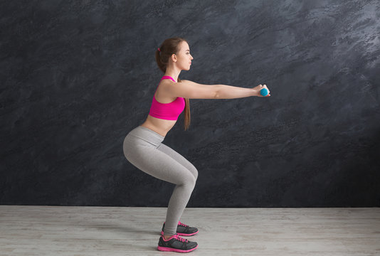 Fitness woman doing squat on grey background