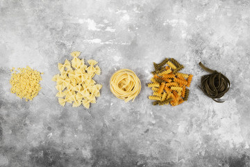 Various raw pasta on gray background. Top view. Food background