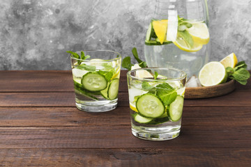 Detox drink with cucumber, lemon and mint in glasses on a wooden background. Copy space. Food background