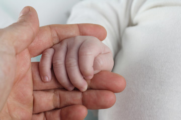 mano de niño recién nacido entre los dedos de su mamá