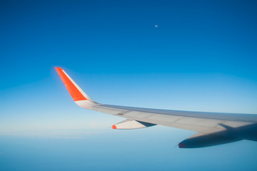 Fototapeta na wymiar airplane wing on blue sky with the moon in the distance