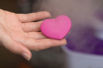 St Valentine's symbol: woman's hands holding a little heart next to the chest where a real heart is situated