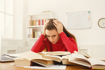 Student girl studying at table full of books