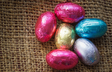 Chocolate easter eggs wrapped in colorful aluminum foil on brown net with vintage tone style, Delicious chocolate easter eggs in holiday easter day concept.;