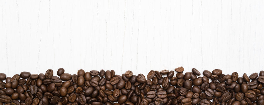 Roasted of coffee beans on white wood background.