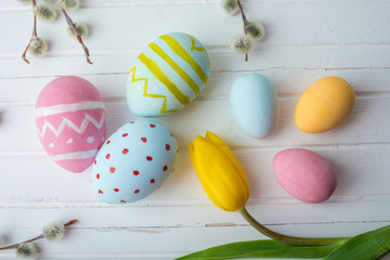 Fototapeta na wymiar Colorful Easter eggs with yellow Tulip hand painted on a white wooden background. Festive spring card
