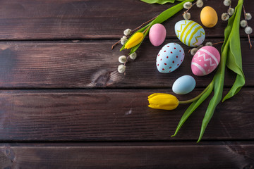 Colorful Easter eggs with yellow Tulip hand painted on a dark wooden background. Holiday spring card