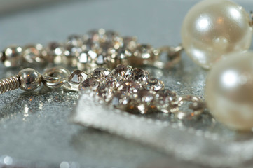 Silver earrings with gems and pearls on shiny gift box close up macro shot.
