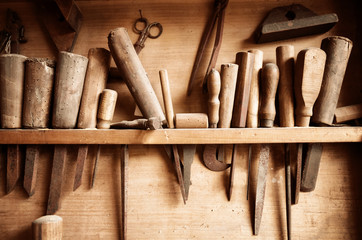 Vintage colored image of carpenter tools hanging from the wall of a dusty workshop