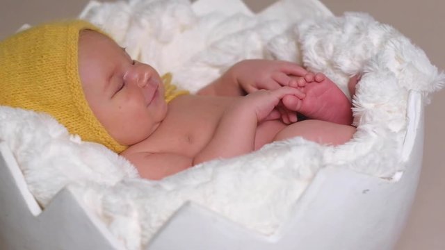 Lovely newborn child in yellow hat sleeping on white soft blanket