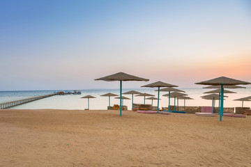 Parasols on the beach of Red Sea in Hurghada at sunrise, Egypt