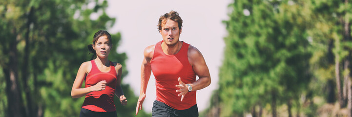 Running fitness couple runners working out sport in outdoor nature landscape. Active living man and woman jogging training in summer banner panorama. Asian girl, caucasian athletes.