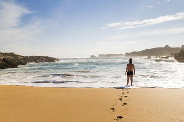 woman walking through the sand of a lonely and beautiful beach
