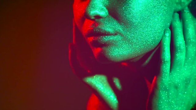 Fashion model woman in colorful bright sparkles and neon lights posing in studio, portrait of beautiful sexy girl. Art design colorful vivid makeup. 4K UHD video footage. 3840X2160