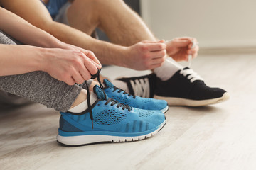Couple tying up laces on sport shoes closeup