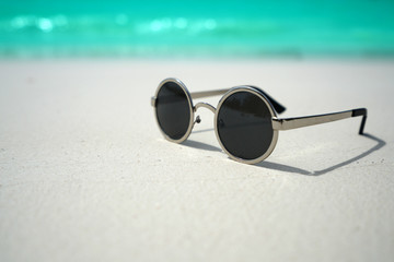 Fototapeta na wymiar Sunglasses on sandy beach in summer.