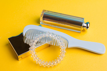 Blue small hair brush and spiral hair clip, lipstick on a yellow background