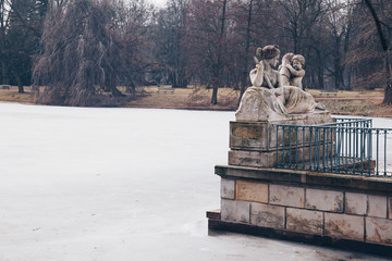 Allegory of the Vistula River by Ludwik Kauffman with frozen lake in Warsaw Royal Baths Park in winter - obrazy, fototapety, plakaty