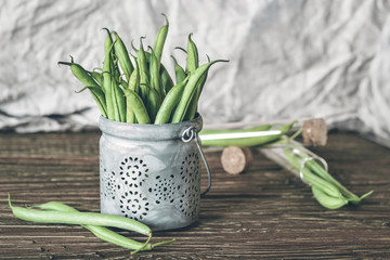 Fresh organic green beans in a metallic bowl on a rustic wooden table