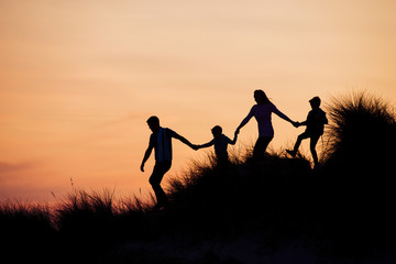 Fototapeta premium Silhouette of Family Running Through the Sand Dunes