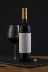 Isolated Red Wine Bottle in a Black, wood Background and White Label