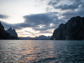 Boat trip on water surface of a tropical lake, mountains, cliffs and rocks on sunset background, Khao Sok National Park, Surat Thani, Thailand