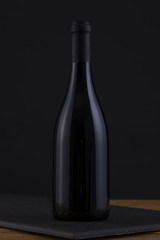 Fototapeta na wymiar Isolated Red Wine Bottle in a Black, wood Background and Black Label