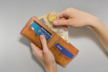 Portafoglio aperto con bitcoin cartacei e carte di credito virtuali, sfondo acciaio satinato - obrazy, fototapety, plakaty