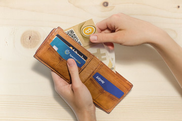 Portafoglio aperto con bitcoin cartacei e carte di credito virtuali, sfondo legno - obrazy, fototapety, plakaty