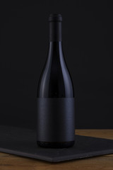 Isolated Red Wine Bottle in a Black, wood Background and Black Label