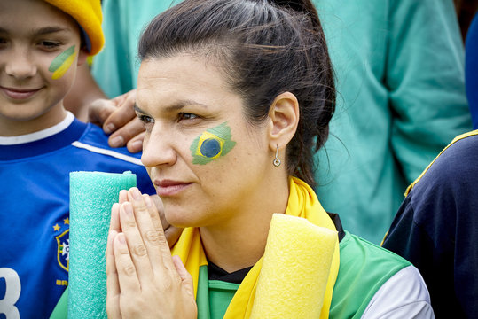 Brazilian football supporter clasping hands together in prayer at match