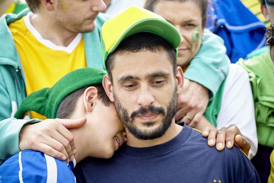 Brazilian football fans consoling each other at match