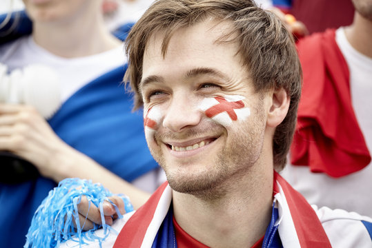 British football fan smiling cheerfully at match, portrait