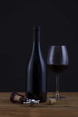 Isolated Red Wine Bottle in a Black Background and Glass