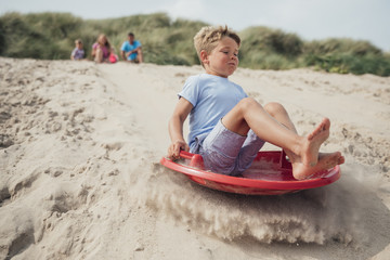 Little Boy Sliding Down a Sand Dune